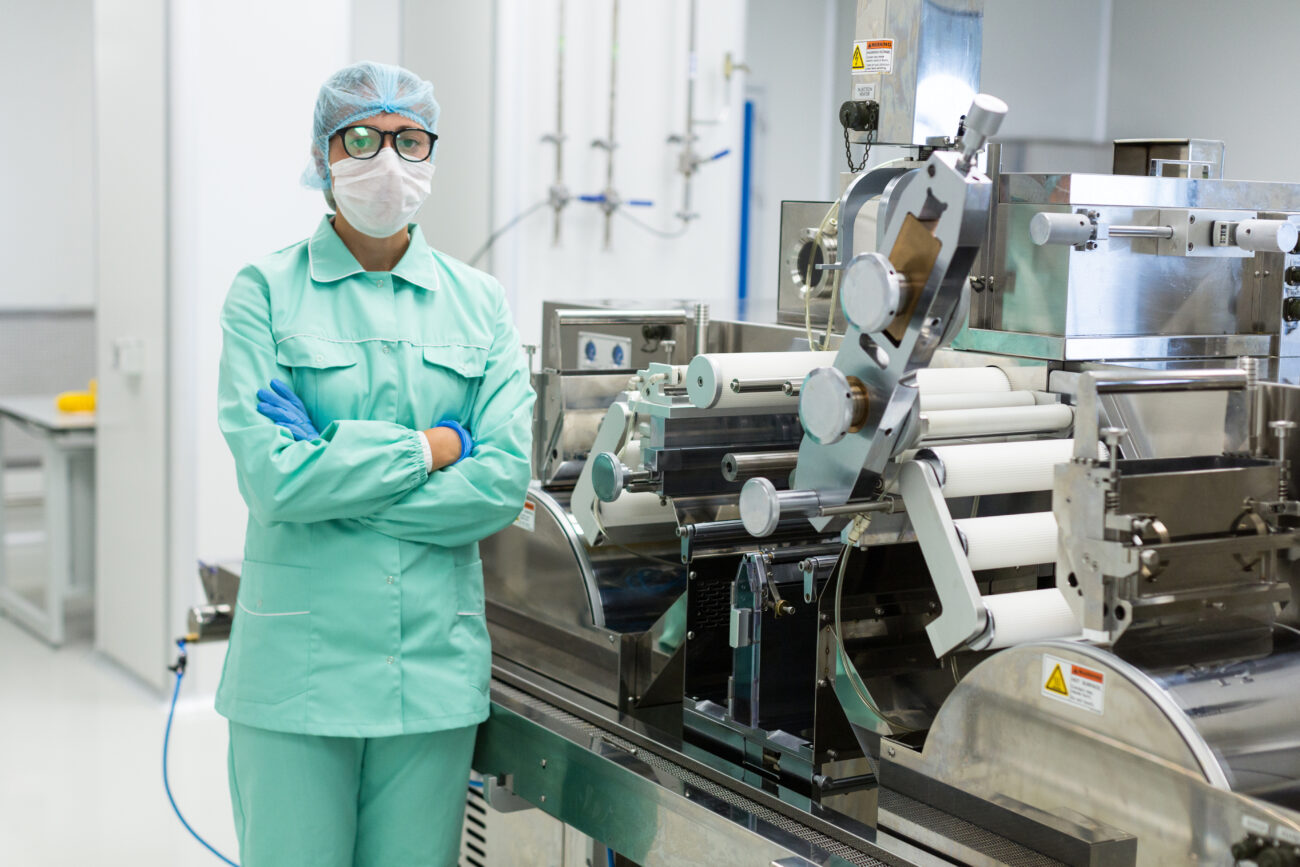 scientist blue suit is standing near manufacture machine